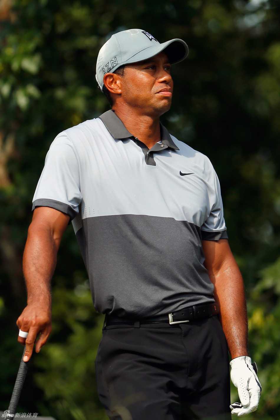 伍兹行走在球道上，手扶后腰，显露出背伤带来的不适，但步伐依然向前。