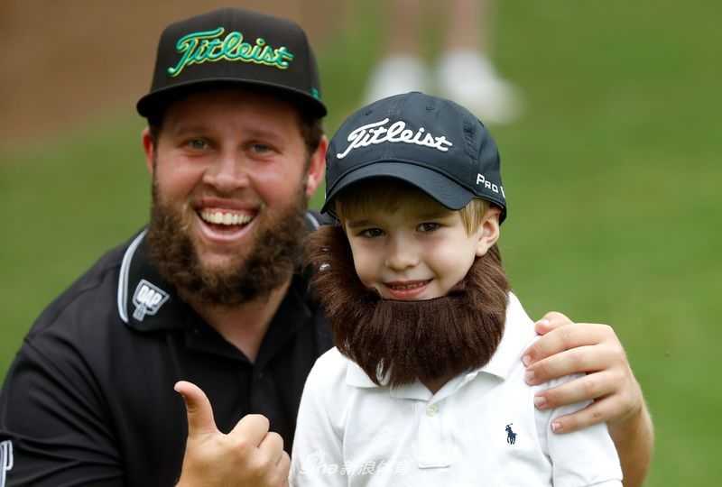 西班牙名将塞尔吉奥·加西亚侧身站在围栏旁，神情专注，手持马克笔为一位球迷的纪念品签名。