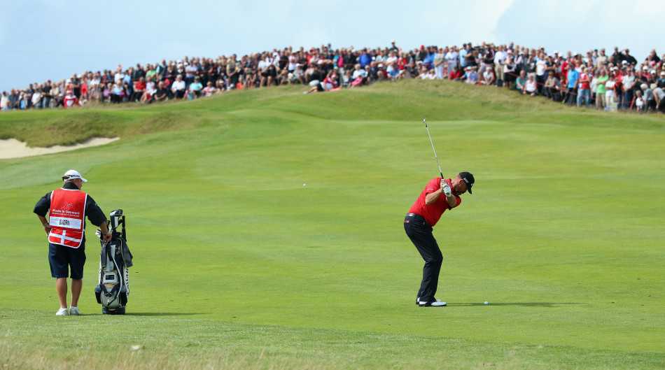 沃克菲尔德与球童正在果岭上全神贯注地研判推杆线路，每一厘米都关乎胜负。