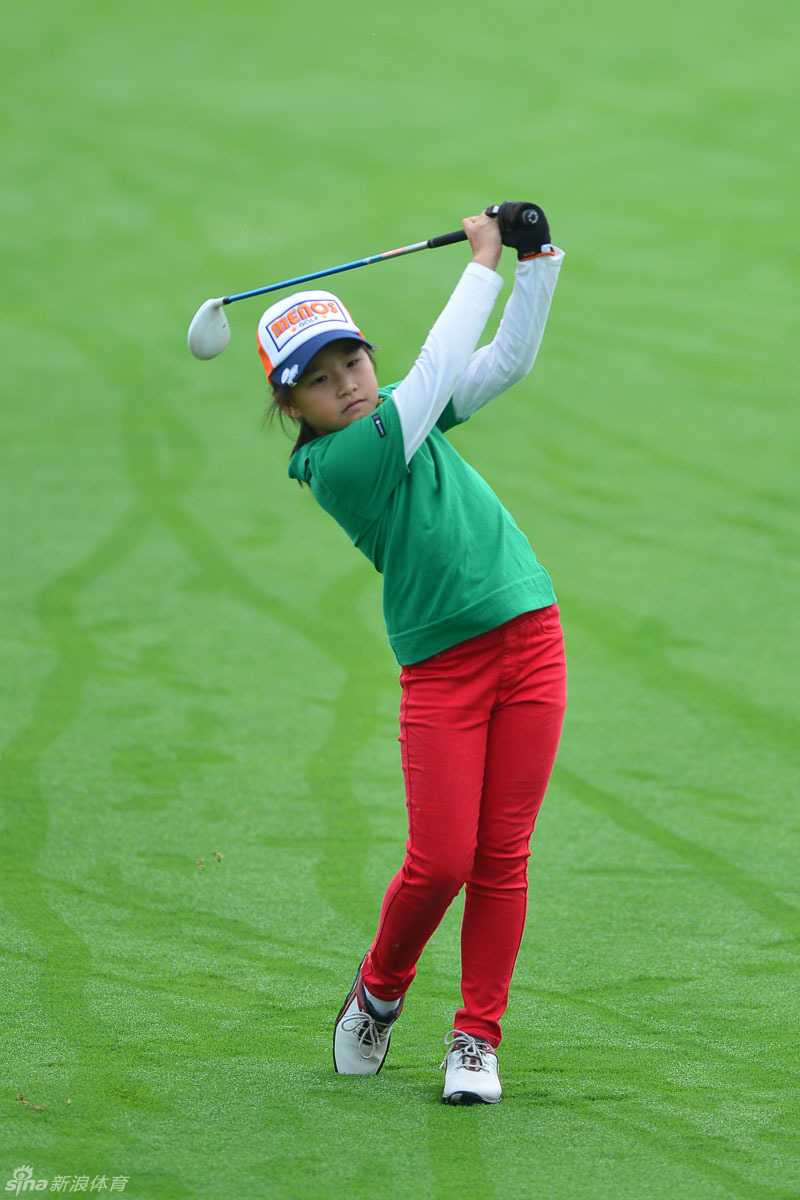 果岭上，小女孩俯身专注地观察推杆线路，她的父亲站在侧后方，同样弯着腰，目光与她看向同一方向，仿佛在进行一场无声的战术交流。