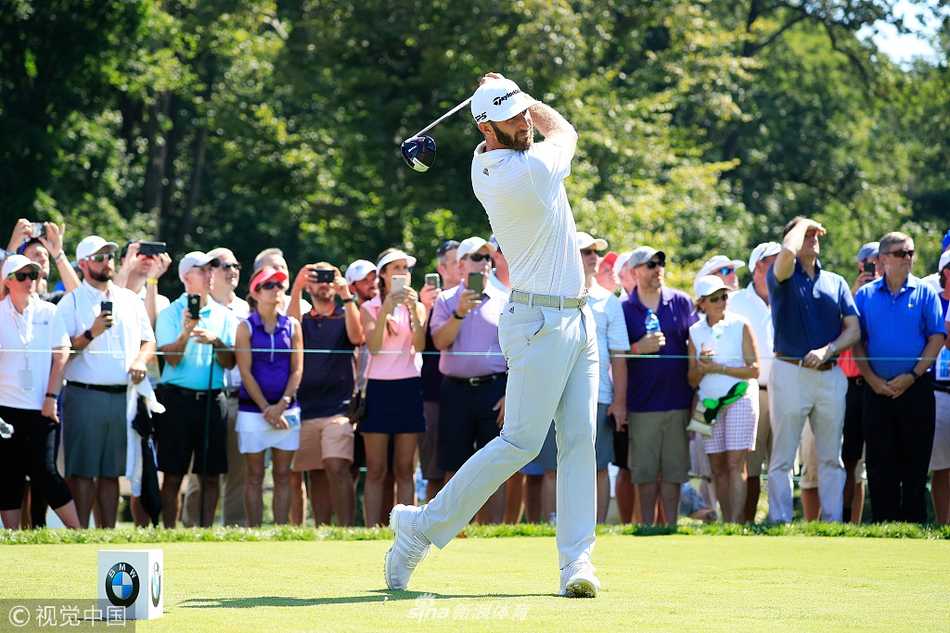 BMW锦标赛首轮赛场全景，绿意盎然的球道与点缀其间的沙坑、水塘构成一幅美丽画卷，球员与观众的身影点缀其中，气氛宁静而紧张。