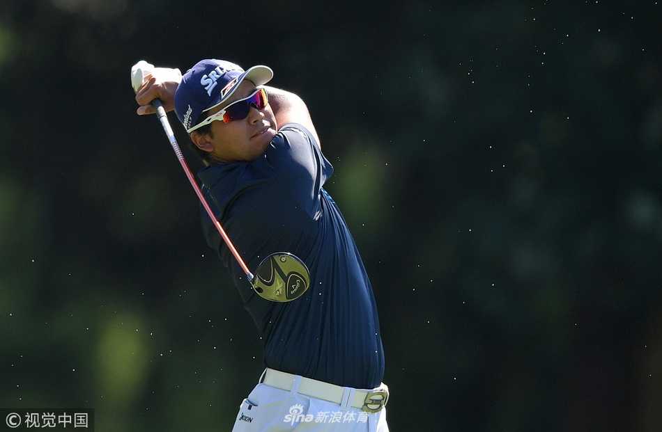 一名球员在开球台上完成大幅度的上杆动作，背影充满力量感，广阔的球场与天空作为背景，凸显了高尔夫运动的优雅与力量结合之美。