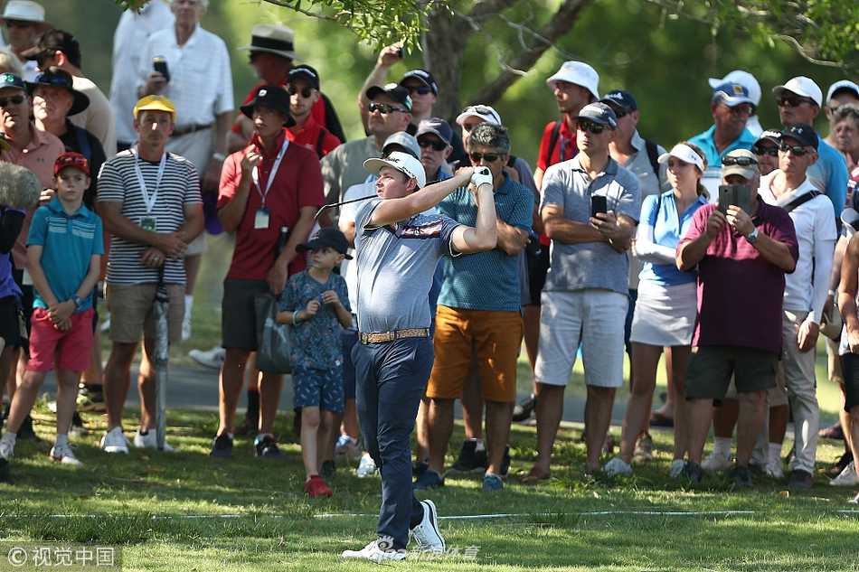 观众聚集在果岭周围，屏息凝神观看球员推杆，现场充满了紧张与期待的氛围