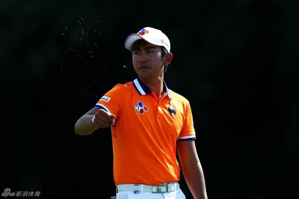 韩国选手安秉勋在发球台上全力开球，动作流畅有力，白色的高尔夫球在蓝天背景下划出一道清晰弧线。