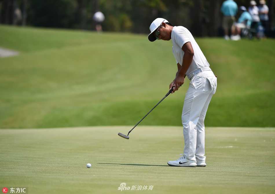 李昊桐在果岭边进行细致的切杆准备，认真研究草纹与坡度对小球的影响。