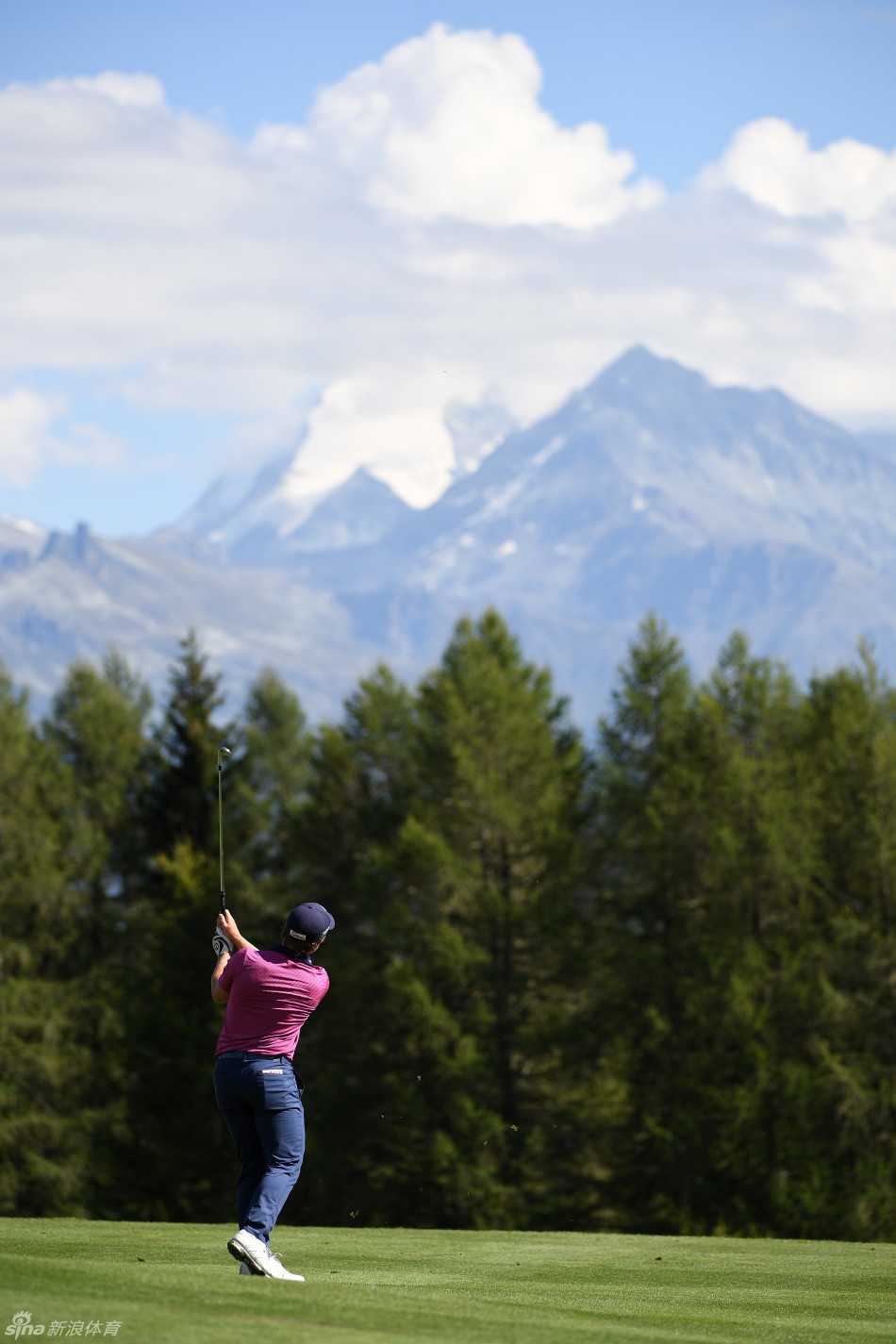 高尔夫球飞越清澈的湖水，在蓝天白云下划出优美弧线，落向对岸的球道