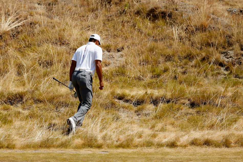 伍兹成功将小球从复杂地形中救出并送上果岭后，他仔细地俯身标记小球位置，脸上带着专注而平静的神情。