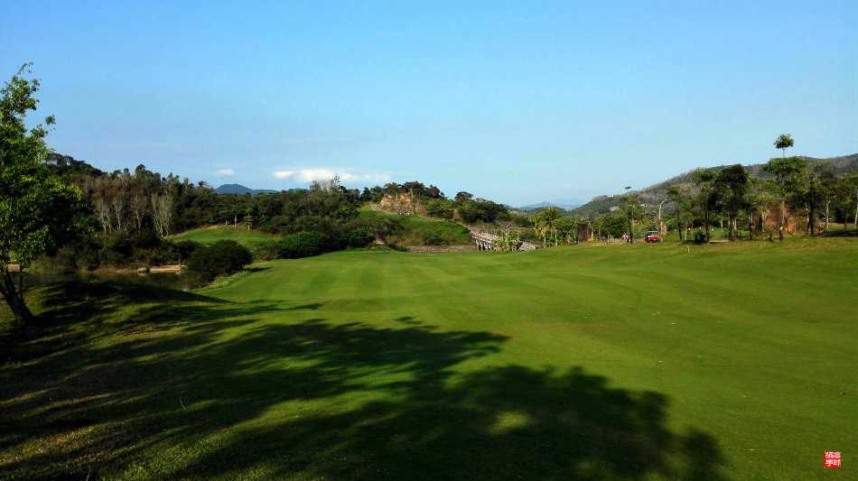夕阳余晖洒在球场水域上，金波粼粼，远处球洞旗帜在微风中轻扬