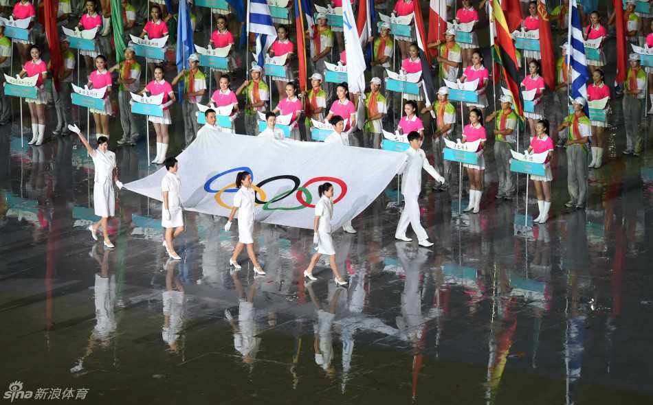 奥林匹克五环旗在南京青奥会开幕式会场中央高高飘扬，八位执旗手在其映衬下成为剪影，象征着奥林匹克精神的永恒与传承